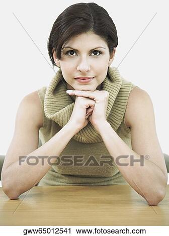 Portrait of a young woman sitting with her hand on her chin View Large Photo Image Stock Image - Portrait of a young woman sitting with her hand on her chin. Fotosearch
