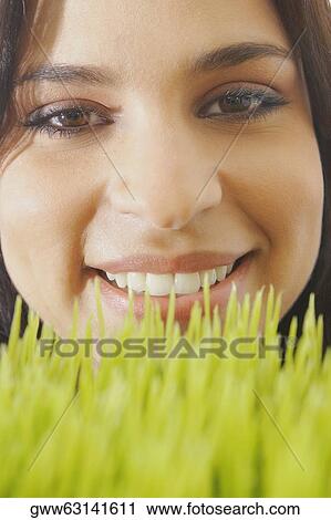 Portrait of a young woman smiling over wheatgrass View Large Photo Image Stock Image - Portrait of a young woman smiling over wheatgrass. Fotosearch