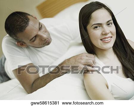 Portrait of a young woman smiling with a mid adult man lying on the bed View Large Photo Image Stock Image - Portrait of a young woman smiling with a mid adult man lying on the bed. Fotosearch