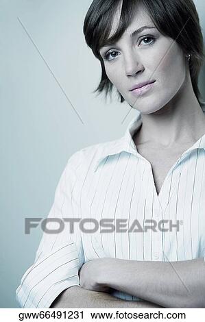 Portrait of a young woman smiling with her arms crossed View Large Photo Image Stock Image - Portrait of a young woman smiling with her arms crossed. Fotosearch