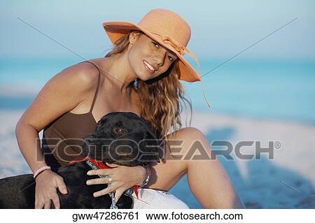 Portrait of a young woman stroking a dog on the beach View Large Photo Image Stock Image - Portrait of a young woman stroking a dog on the beach. Fotosearch
