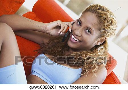Portrait of a young woman talking on a mobile phone and smiling View Large Photo Image Stock Image - Portrait of a young woman talking on a mobile phone and smiling. Fotosearch