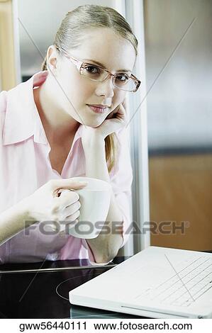 Stock Image - Portrait of a young woman talking on a mobile phone and holding a cup of tea. Fotosearch