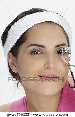 Portrait of a young woman using a eyelash curler View Large Photo Image Stock Image - Portrait of a young woman using a eyelash curler. Fotosearch