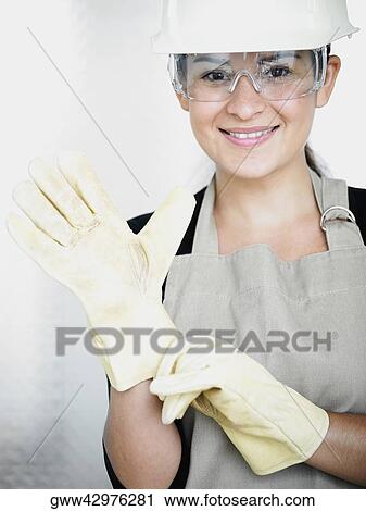 Portrait of a young woman wearing protective gloves and smiling View Large Photo Image Stock Image - Portrait of a young woman wearing protective gloves and smiling. Fotosearch