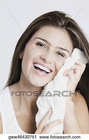 Stock Image - Portrait of a young woman wiping her face with a towel and smiling. Fotosearch