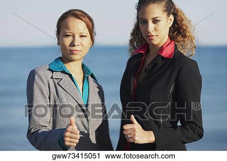 Portrait of two young women showing thumbs up signs View Large Photo Image Stock Image - Portrait of two young women showing thumbs up signs. Fotosearch