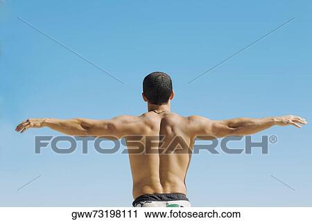 Rear view of a mid adult man standing with his arms outstretched View Large Photo Image Stock Image - Rear view of a mid adult man standing with his arms outstretched. Fotosearch