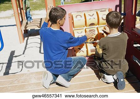 Rear view of a teenage boy and a boy playing tic-tac-toe View Large Photo Image Stock Image - Rear view of a teenage boy and a boy playing tic-tac-toe. Fotosearch