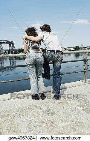 Rear view of a young couple leaning against a railing View Large Photo Image Stock Image - Rear view of a young couple leaning against a railing. Fotosearch