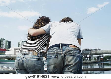 Rear view of a young couple leaning against a railing View Large Photo Image Stock Image - Rear view of a young couple leaning against a railing. Fotosearch