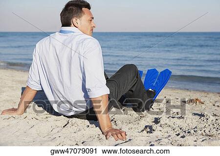 Rear view of a young man wearing flippers and sitting on the beach View Large Photo Image Stock Image - Rear view of a young man wearing flippers and sitting on the beach. Fotosearch
