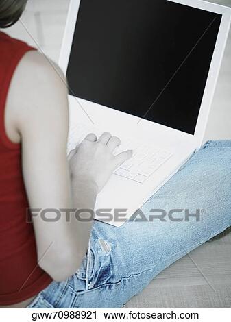 Rear view of a young woman using a laptop View Large Photo Image Stock Image - Rear view of a young woman using a laptop. Fotosearch