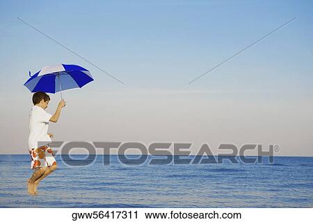 Side profile of a boy jumping with an umbrella View Large Photo Image Stock Image - Side profile of a boy jumping with an umbrella. Fotosearch