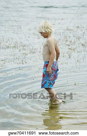 Side profile of a boy standing in water View Large Photo Image Stock Image - Side profile of a boy standing in water. Fotosearch