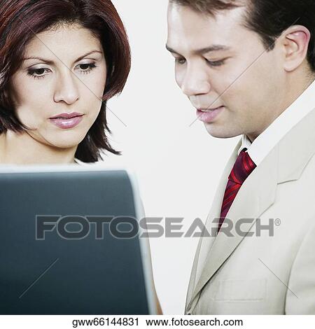 Side profile of a businessman and a businesswoman looking at a laptop View Large Photo Image Stock Image - Side profile of a businessman and a businesswoman looking at a laptop. Fotosearch