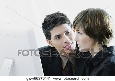 Side profile of a businesswoman looking at a computer monitor with a businessman looking at her View Large Photo Image Stock Image - Side profile of a businesswoman looking at a computer monitor with a businessman looking at her. Fotosearch
