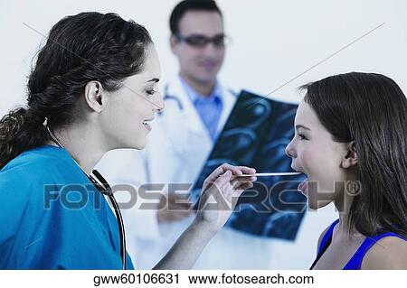 Side profile of a female doctor examining a girl's mouth with a tongue depressor View Large Photo Image Stock Image - Side profile of a female doctor examining a girl's mouth with a tongue depressor. Fotosearch