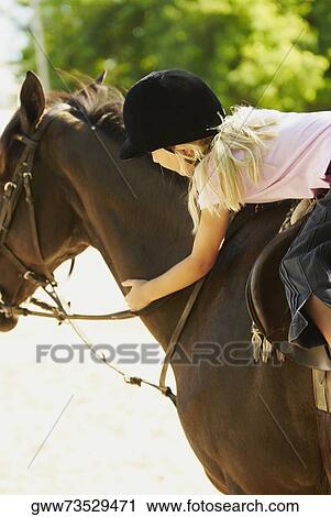 Stock Image - Side profile of a girl horseback riding. Fotosearch