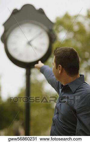 Side profile of a mid adult man pointing towards a clock View Large Photo Image Stock Image - Side profile of a mid adult man pointing towards a clock. Fotosearch