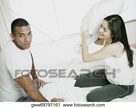 Side profile of a mid adult man with a young woman having a pillow fight on the bed View Large Photo Image Stock Image - Side profile of a mid adult man with a young woman having a pillow fight on the bed. Fotosearch