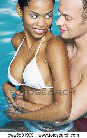 Side profile of a young couple embracing each other in the swimming pool View Large Photo Image Stock Image - Side profile of a young couple embracing each other in the swimming pool. Fotosearch
