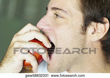 Side profile of a young man eating an apple View Large Photo Image Stock Image - Side profile of a young man eating an apple. Fotosearch