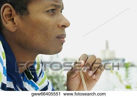 Side profile of a young man holding a drinking straw View Large Photo Image Stock Image - Side profile of a young man holding a drinking straw. Fotosearch