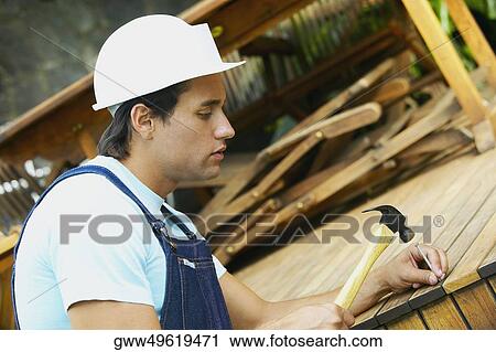 Side profile of a young man nailing a wooden plank View Large Photo Image Stock Image - Side profile of a young man nailing a wooden plank. Fotosearch