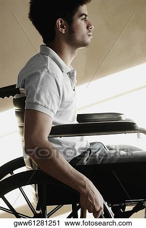 Stock Image - Side profile of a young man sitting in a wheelchair. Fotosearch