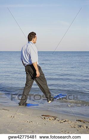 Side profile of a young man wearing flippers and walking on the beach View Large Photo Image Stock Image - Side profile of a young man wearing flippers and walking on the beach. Fotosearch