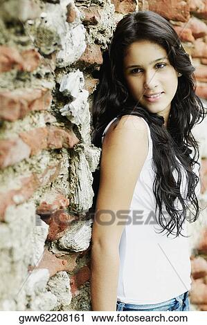 Stock Image - Side profile of a young woman leaning against a wall. Fotosearch