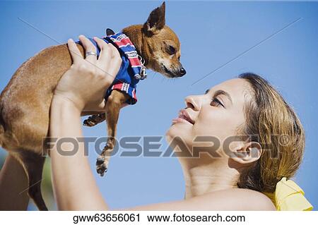 Stock Image - Side profile of a young woman picking up her pets. Fotosearch
