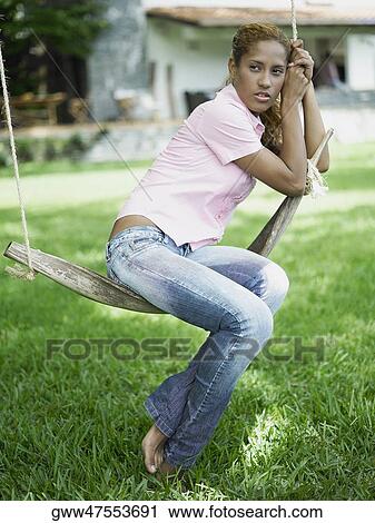 Side profile of a young woman sitting on a swing and looking upset View Large Photo Image Stock Image - Side profile of a young woman sitting on a swing and looking upset. Fotosearch