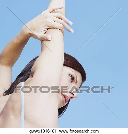Stock Image - Side profile of a young woman stretching her arms. Fotosearch
