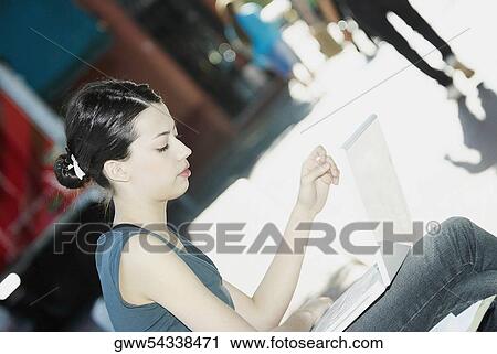 Stock Image - Side profile of a young woman using a laptop. Fotosearch