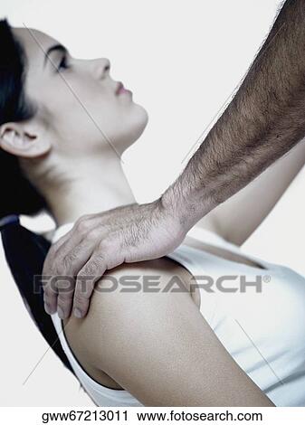 Stock Image - Side profile of a young woman with a man's hands on her shoulders. Fotosearch