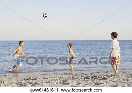 Two boys and a teenage boy playing soccer on the beach View Large Photo Image Stock Image - Two boys and a teenage boy playing soccer on the beach. Fotosearch