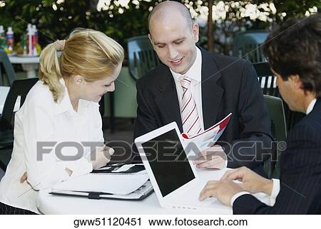 Two businessmen with a businesswoman sitting at the table View Large Photo Image Stock Image - Two businessmen with a businesswoman sitting at the table. Fotosearch