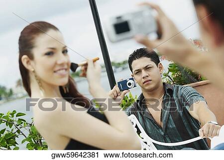 Two young men taking a picture of a young woman applying make-up View Large Photo Image Stock Image - Two young men taking a picture of a young woman applying make-up. Fotosearch