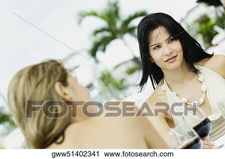 Two young women sitting at the table with glasses of wine in front of them View Large Photo Image Stock Image - Two young women sitting at the table with glasses of wine in front of them. Fotosearch