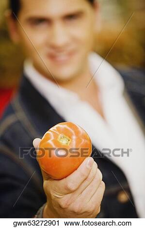 Stock Image - Young man holding a tomato. Fotosearch