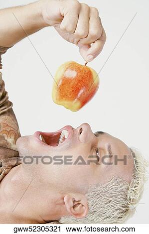 Young man holding an apple with his mouth open View Large Photo Image Stock Image - Young man holding an apple with his mouth open. Fotosearch