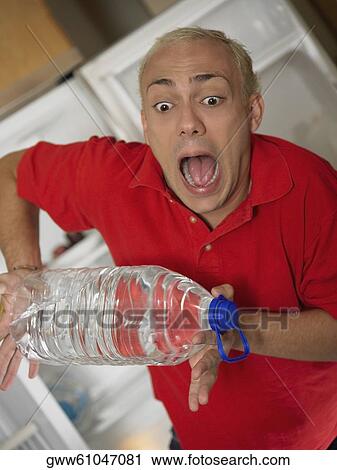 Young man looking at a water bottle slipping from his hands View Large Photo Image Stock Image - Young man looking at a water bottle slipping from his hands. Fotosearch