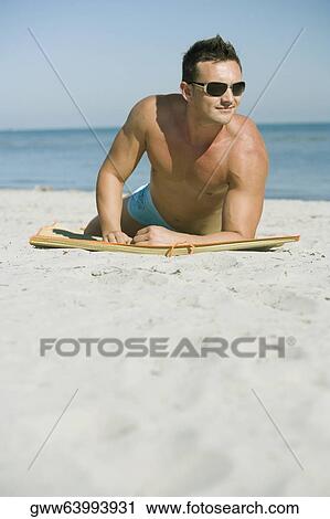 Young man lying on the beach View Large Photo Image Stock Image - Young man lying on the beach. Fotosearch