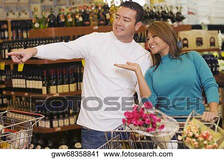 Young woman and a mid adult man standing in a supermarket and smiling View Large Photo Image Stock Image - Young woman and a mid adult man standing in a supermarket and smiling. Fotosearch