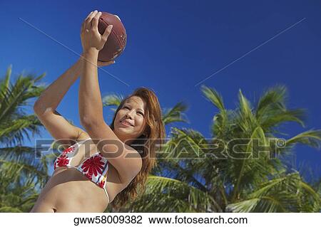 Stock Image - Young woman holding a rugby ball. Fotosearch