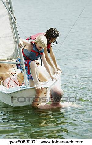 Boy and his sister looking at a man swimming beside a sailboat View Large Photo Image Stock Image - Boy and his sister looking at a man swimming beside a sailboat. Fotosearch