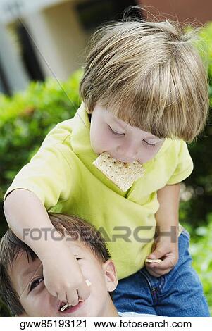Boy feeding a biscuit to another View Large Photo Image Stock Image - Boy feeding a biscuit to another. Fotosearch