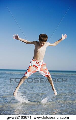 Stock Image - Boy jumping in water with his arms outstretched. Fotosearch
